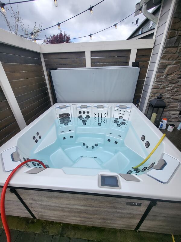 Immaculate premium spa filling with crystal-clear water on a covered deck